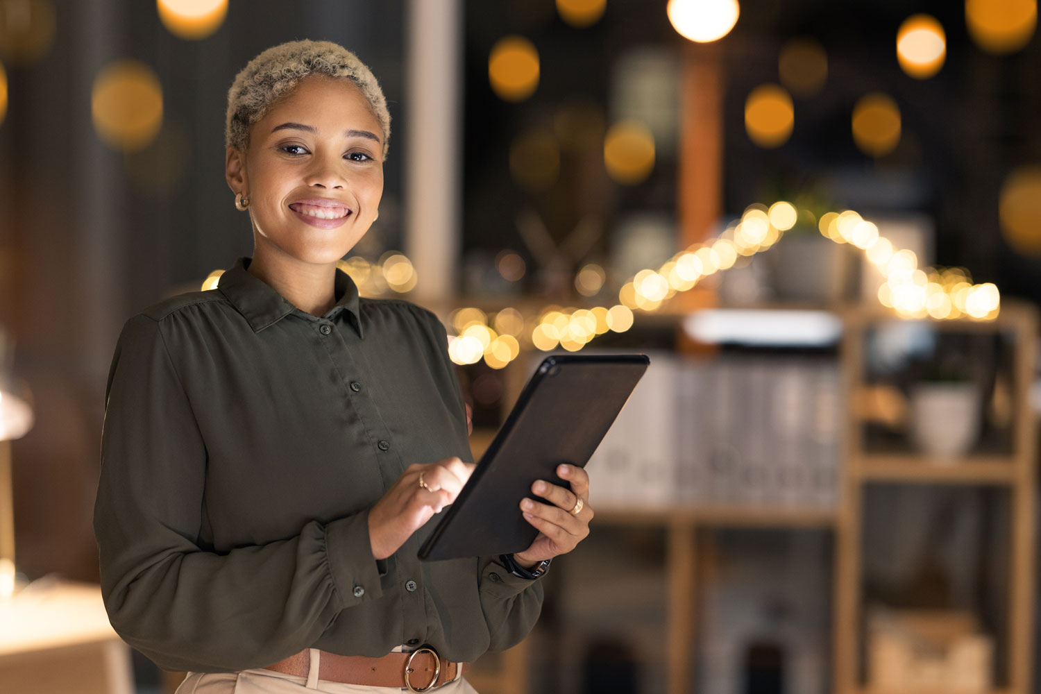 A woman smiles as she looks up from her tablet